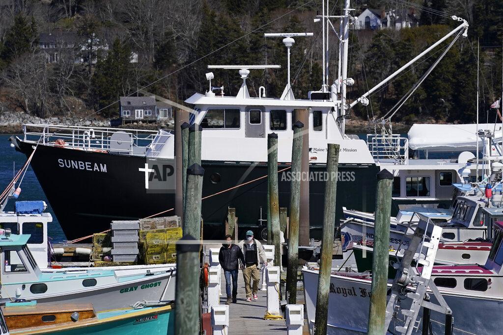 Robert F. Bukaty Marc Nighman and Jonathan Partin leave the Sunbeam after receiving a COVID-19 vaccination, Friday, March 19, 2021, in Northeast Harbor, Maine. The 74-foot vessel operated by the non-profit Maine Seacoast Mission, seen in the background, has vaccinated hundreds of islanders. (AP Photo/Robert F. Bukaty)