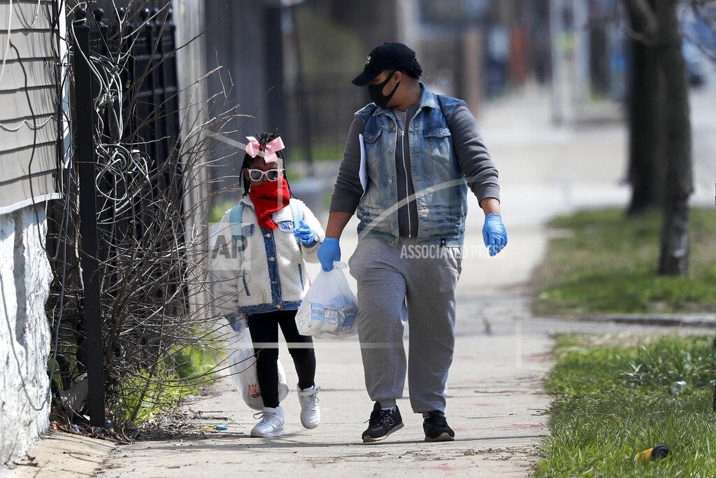Charles Rex Arbogast In this April 7, 2020, photo, Erica Harris, right, and her daughter Jordan, wear their protective masks as they walk back home after getting a lunch and homework from the child’s school on Chicago’s Southside in Chicago. As the coronavirus tightened its grip across the country, it is cutting a particularly devastating swath through an already vulnerable population, black Americans. (AP Photo/Charles Rex Arbogast)