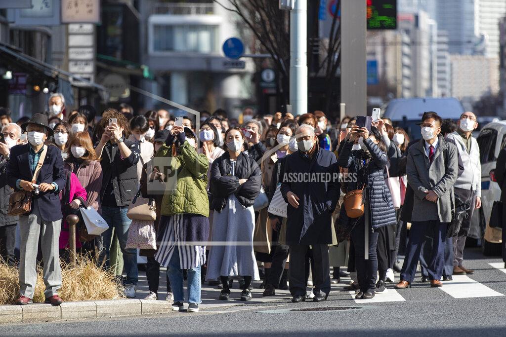 Hiro Komae Some of the bystanders waiting at a traffic intersection take pictures of a clock on a building when the 10th annual tribute started at 2:46 p.m. for the victims of a 2011 disaster in Tokyo Thursday, March 11, 2021. Japan is marking the 10th anniversary Thursday of the earthquake, tsunami and nuclear disaster that hit the northeastern region. (AP Photo/Hiro Komae)