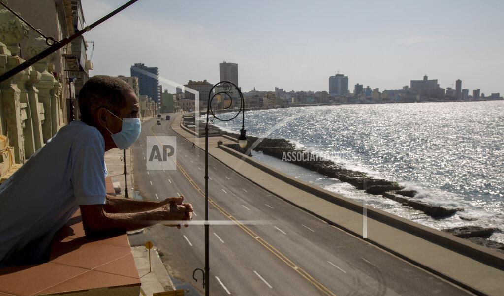 Ismael Francisco Restaurant worker Julio Diago looks over the empty road along the Malecon sea wall from the Nazdarovie restaurant, which is closed amid the lockdown to help contain the spread of the new coronavirus in Havana, Cuba, Monday, April 27, 2020. Many restaurants are closed while only work considered essential is allowed to continue. (AP Photo/Ismael Francisco)