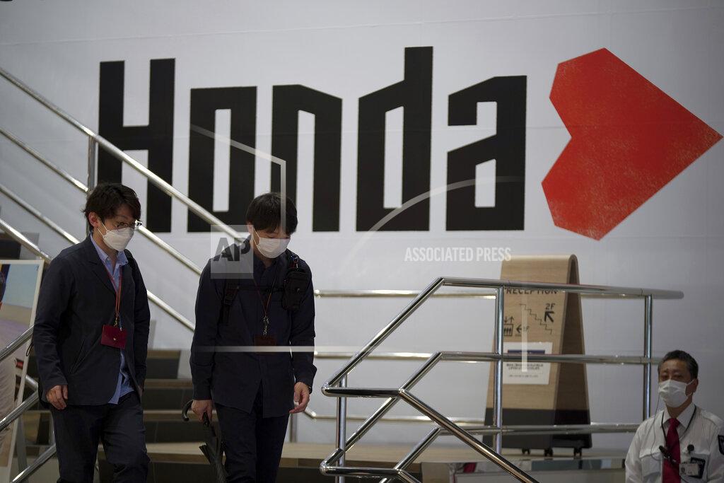 Eugene Hoshiko People walk near the logo of Honda Motor Company at a showroom Friday, May 13, 2022, in Tokyo. Honda’s fiscal fourth quarter profit slipped to almost half of what the Japanese automaker earned the previous year amid headwinds of supply shortages and rising raw material costs. (AP Photo/Eugene Hoshiko)