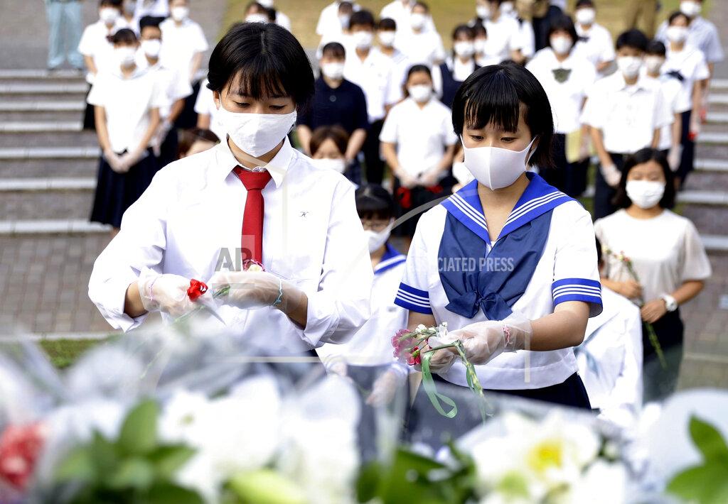 085123+0900 High school students offer flowers for the victims of U.S. atomic bombing in front of a monument at the Atomic Bomb Hypocenter Park in Nagasaki, southern Japan, Sunday, Aug. 9, 2020. Nagasaki marked the 75th anniversary of the atomic bombing on Sunday. (Kyodo News via AP)