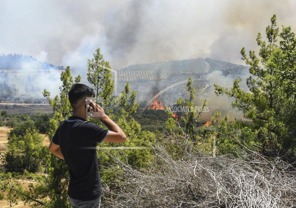Uncredited A man watches wildfires in Kacarlar village near the Mediterranean coastal town of Manavgat, Antalya, Turkey, Saturday, July 31, 2021. The death toll from wildfires raging in Turkey's Mediterranean towns rose to six Saturday after two forest workers were killed, the country's health minister said. Fires across Turkey since Wednesday burned down forests, encroaching on villages and tourist destinations and forcing people to evacuate. (AP Photo)