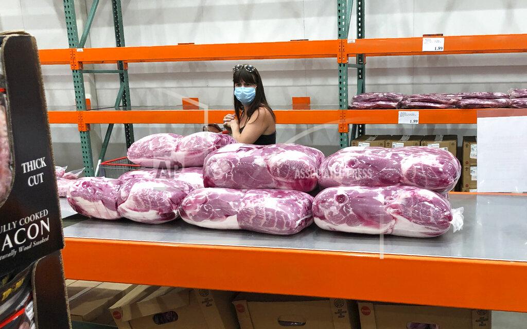 A shopper in a face mask looks over cuts of beef piled up in a cold room for purchase at a Costco warehouse store Tuesday, May 5, 2020, in west Denver. The U.S. economy rebounded at an even-stronger pace in the July-September quarter than first reported but a resurgence in the coronavirus is expected to slow growth sharply in the current quarter with some analysts even raising the specter of a double-dip recession. (AP Photo/David Zalubowski)