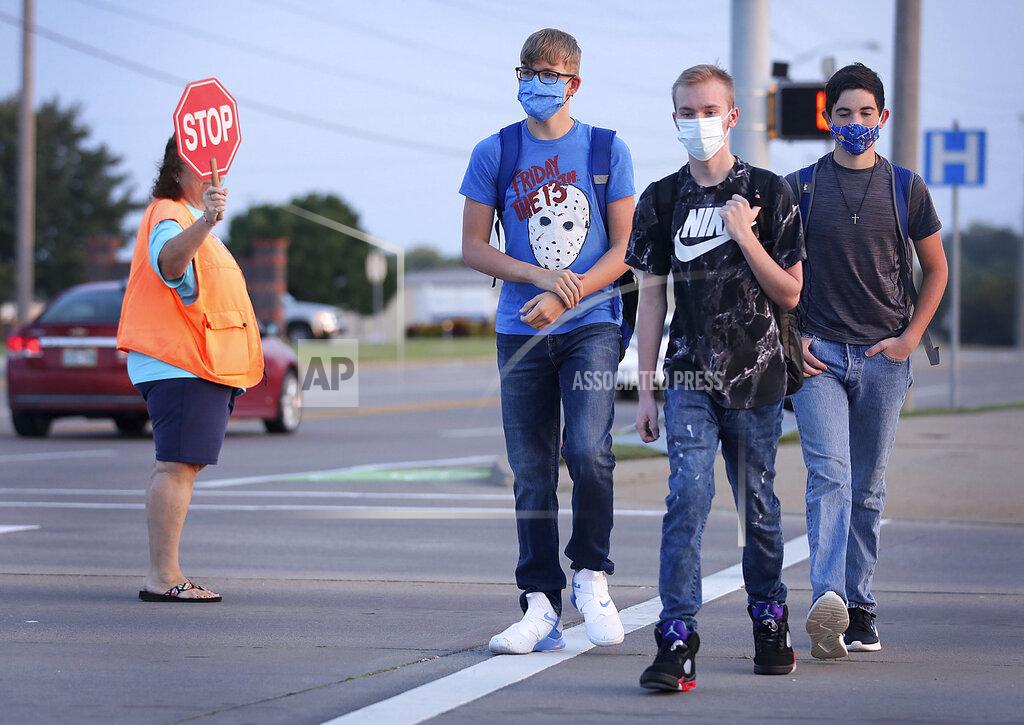 Mike Simons Freshmen Mason Mathis, left, Travis Ryan and Seth Wood make their way to school on the first day of in-person instruction at Owasso schools Thursday, Sept. 17, 2020 in Owasso, Okla. (Mike Simons/Tulsa World via AP)