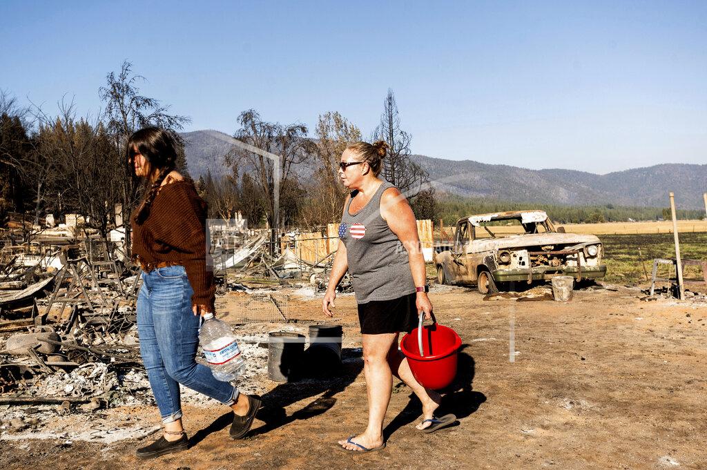 Noah Berger Kimberly Price and granddaughter Kyra Cedillos, 14, walk among burned homes in the Greenville community of Plumas County, Calif., on Sunday, Sept. 5, 2021, while feeding cats left behind by Dixie Fire evacuees. (AP Photo/Noah Berger)