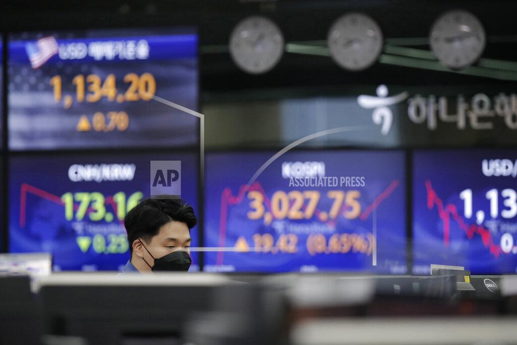 Lee Jin-Man A currency trader stands near the screens showing the Korea Composite Stock Price Index (KOSPI), center, and the foreign exchange rates at the foreign exchange dealing room in Seoul, South Korea, Friday, March 26, 2021. Shares were higher across Asia on Friday after a strong gains on Wall Street driven by hopes for a powerful recovery from the pandemic. (AP Photo/Lee Jin-man)