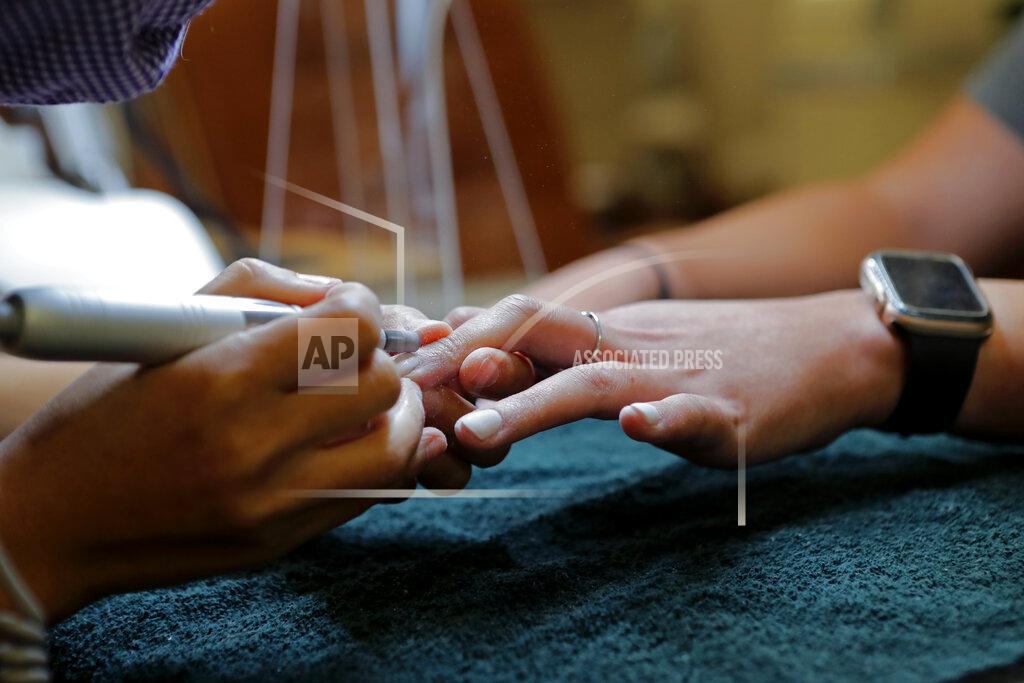 Gerald Herbert Customer Gabi Bustillo gets a manicure through new plexiglass partitions at Luxurie Nail Spa in Harahan, La., Friday, May 15, 2020. Once a hot spot for coronavirus infections, Louisiana is officially easing up Friday on economically devastating business closures and public gathering restrictions that Gov. John Bel Edwards credits with slowing the spread of the virus. (AP Photo/Gerald Herbert)