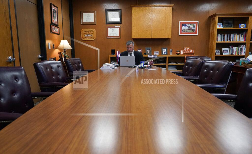 Eric Gay Superintendent Brian Woods, of Northside Independent School District, among the largest districts in Texas works alone at a conference table as he prepares for a virtual meeting, Monday, Feb. 8, 2021, in San Antonio. After seeing two academic years thrown off course by the pandemic, school leaders around the country are planning for the possibility of more distance learning next fall at the start of yet another school year. (AP Photo/Eric Gay)