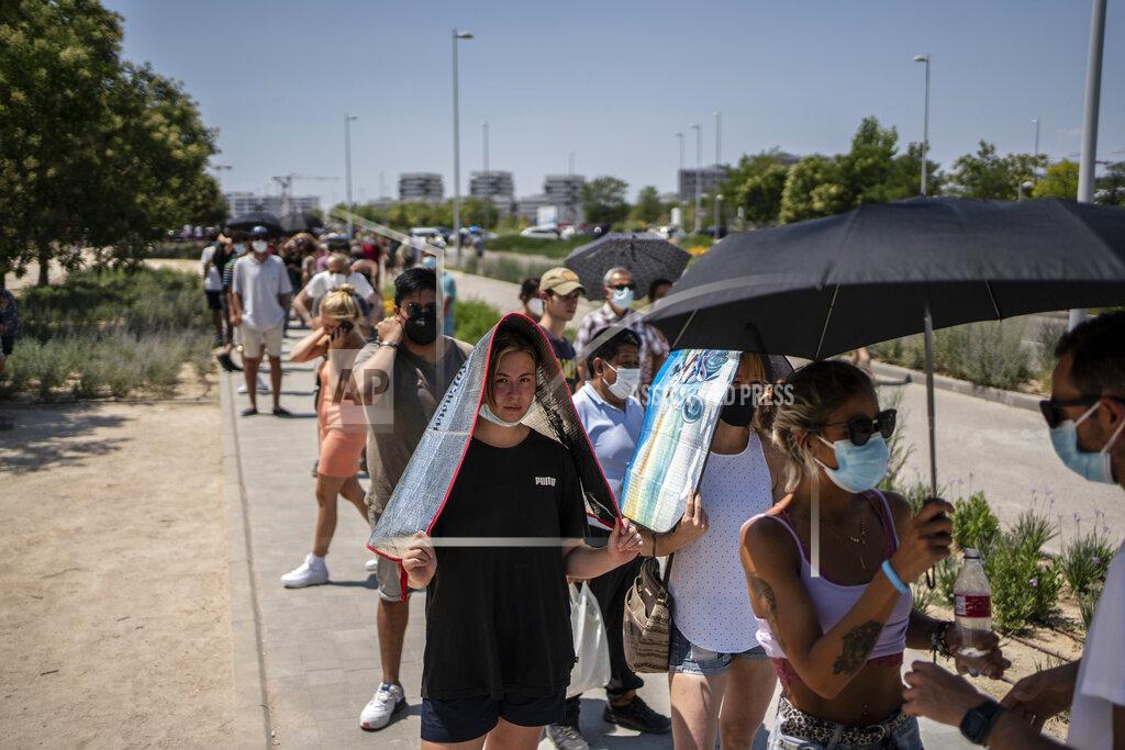 Olmo Calvo People protect themselves from the sun while waiting to be vaccinated against COVID-19 at the Isabel Zendal Hospital in Madrid, Spain, Tuesday, July 20, 2021. Spain is trying to stamp out a new wave of COVID-19 among its youth thanks to a robust vaccination program that is widely supported. Spain like the rest of the European Union got off to a slow start to compared to the United States and Britain when the first vaccines were released. But it has quickly made up ground once deliveries by drug makers started flowing. (AP Photo/Olmo Calvo)