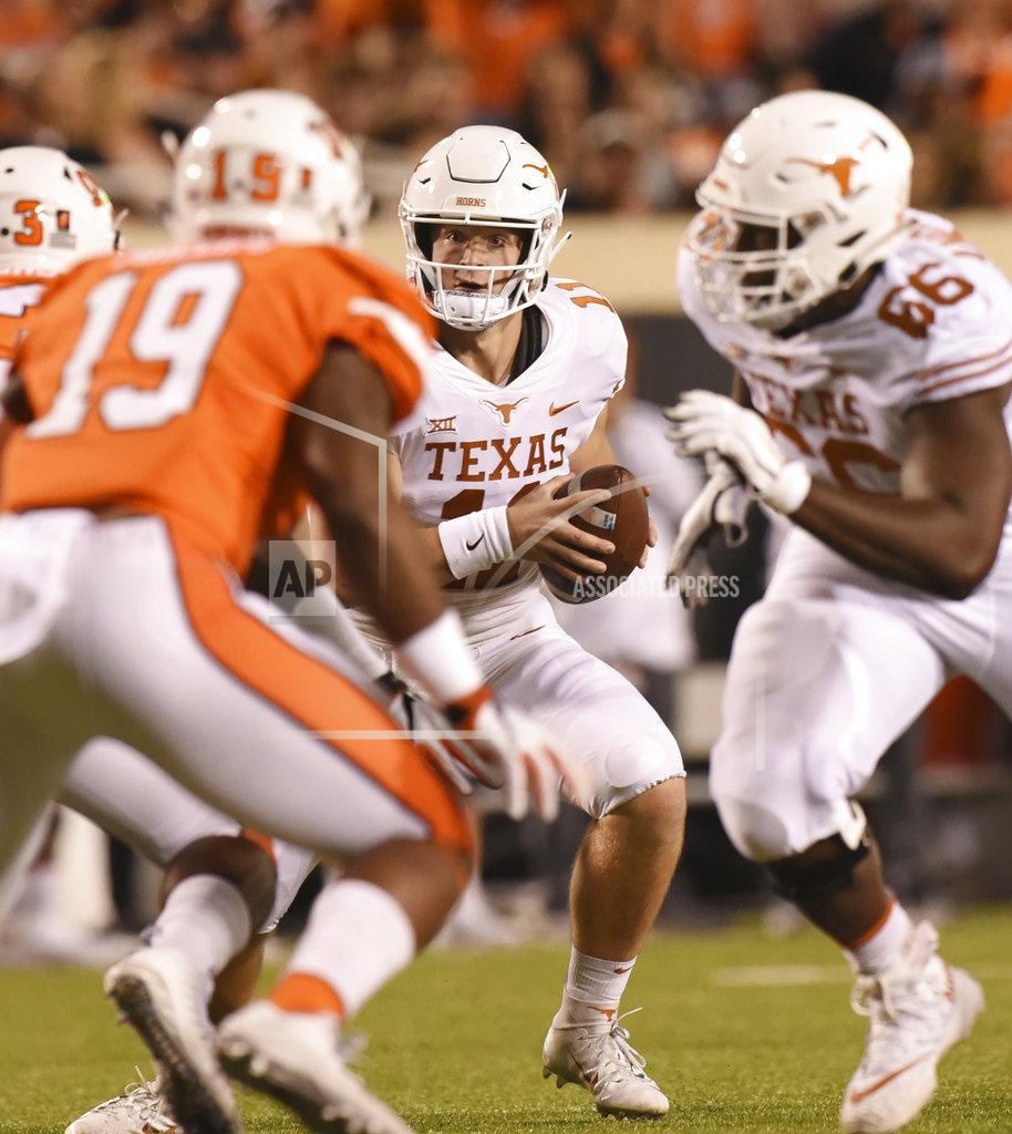 Brody Schmidt Texas quarterback Sam Ehlinger, center, looks at Oklahoma State linebacker Justin Phillips, left, while offensive lineman Calvin Anderson races by in the first half of an NCAA college football game in Stillwater, Okla., Saturday, Oct. 27, 2018. Oklahoma State defeated Texas 35-38.(AP Photo/Brody Schmidt)