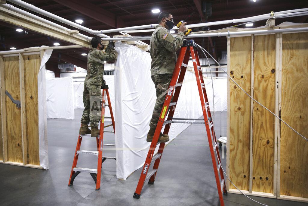 Vermont National Guard Staff Sgt. Micah Erno, left, and Sgt. Jordan Snow run wiring in what will become a makeshift emergency hospital at the Champlain Valley Exposition in Essex Junction, Vt., on Friday, Nov. 20, 2020. By Sunday there will be a 250-bed surge hospital ready in case the COVID-19 pandemic overwhelms Vermont hospitals. (AP Photo/Wilson Ring)