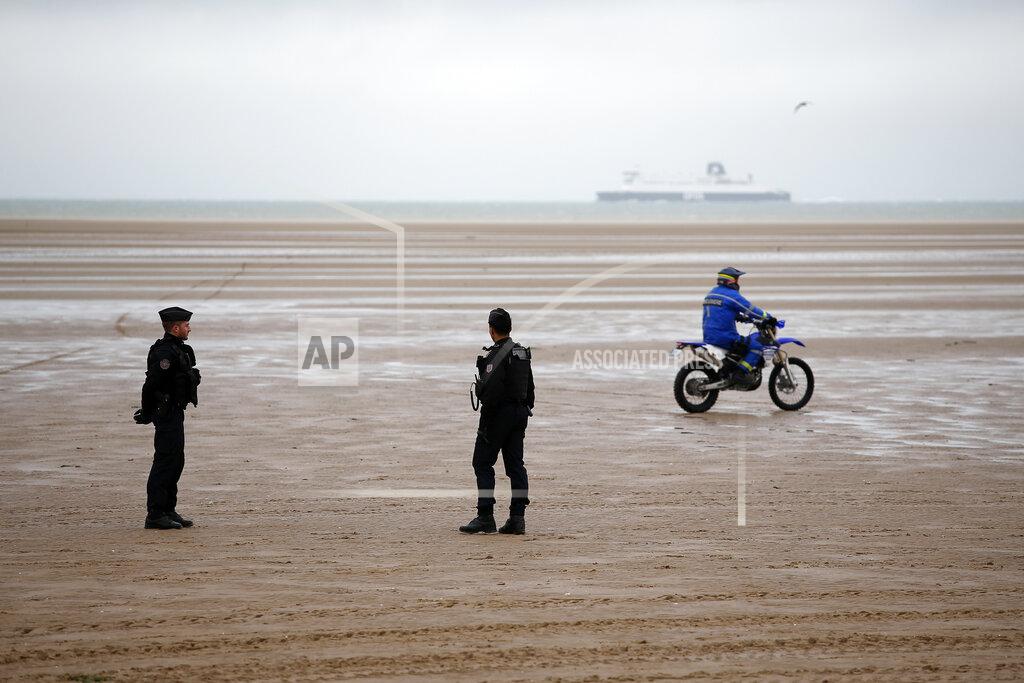 FILE - In this Jan.31, 2020 file photo, police officers patrol on the beach of Oye-Plage, northern France, near Calais. The body of a 16-year-old Sudanese migrant who apparently was trying to reach Britain by sea was found washed up on a French beach Wednesday Aug.19, 2020 in Sangatte, near Calais, authorities said. The discovery comes amid tensions between Britain and France over a rise in migrants' efforts to cross the English Channel in recent weeks. (AP Photo/Michel Spingler, File)