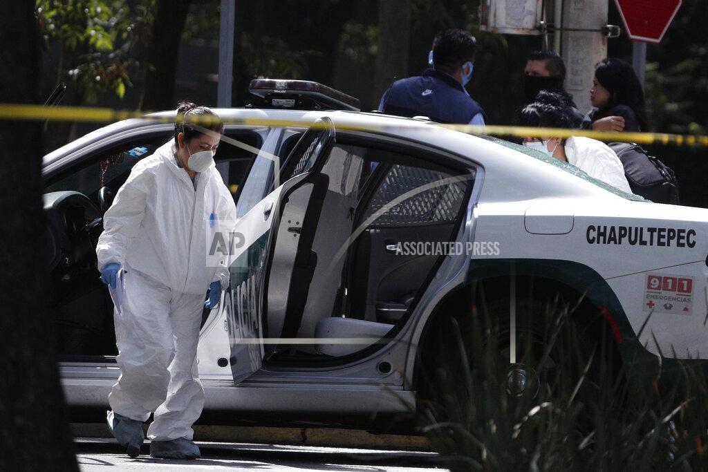 Rebecca Blackwell A forensic investigator inspects a police vehicle at the scene where the Mexican capital's police chief was attacked by gunmen in Mexico City, Friday, June 26, 2020. Heavily armed gunmen attacked and wounded Omar García Harfuch in an operation that left several dead. (AP Photo/Rebecca Blackwell)