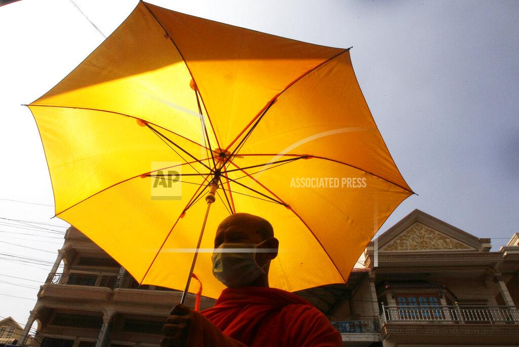 A Buddhist monk wearing a face mask receives alms from devotees in Phnom Penh, Cambodia, Wednesday, March 10, 2021. (AP Photo/Heng Sinith)