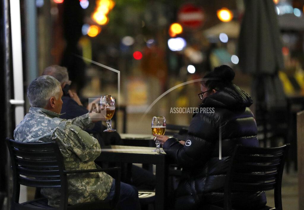 Frank Augstein People drink a beer outside a restaurant in Liverpool, England, Wednesday, Oct. 14, 2020. As the first area in England slapped with strict new restrictions to curb the resurgent coronavirus that have shuttered pubs and imperiled thousands of jobs, Liverpool again feels it's being punished by policies made in Britain's capital, 180 miles (290 kilometers) to the south. (AP Photo/Frank Augstein)