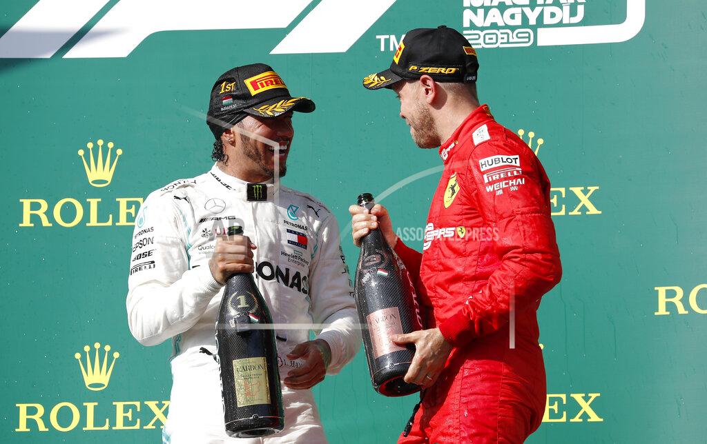 Laszlo Balogh Mercedes driver Lewis Hamilton, left, of Britain, winner of the Hungarian Formula One Grand Prix, smiles on the podium with third placed Ferrari driver Sebastian Vettel, of Germany, at the Hungaroring racetrack in Mogyorod, northeast of Budapest, Hungary, Sunday, Aug. 4, 2019. (AP Photo/Laszlo Balogh)