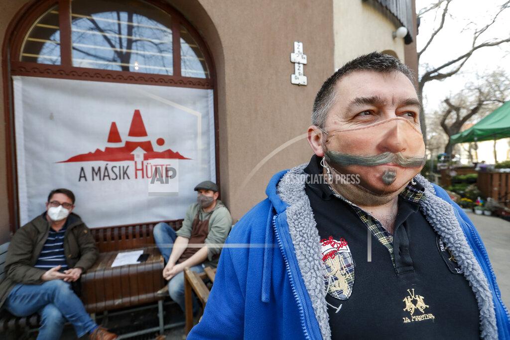 Laszlo Balogh A man wearing a decorated face mask, poses for a photo in Budapest, Hungary, Thursday, March 25, 2021. Hungary, with the world's highest per capita death rate, set a record for daily deaths on Thursday with 252, bringing the death toll to nearly 19,000 in the country, which has a population of less than 10 million. (AP Photo/Laszlo Balogh)