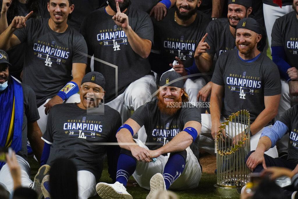Eric Gay FILE - In this Tuesday, Oct. 27, 2020, file photo, Los Angeles Dodgers manager Dave Roberts, left foreground, sits beside third baseman Justin Turner as they pose for a group picture after the Dodgers defeated the Tampa Bay Rays 3-1 in Game 6 to win the baseball World Series in Arlington, Texas. Baseball nearly made it through its version of playoff bubbles unscathed; two innings before the World Series ended, Justin Turner of the now-champion Los Angeles Dodgers Turner was pulled from the game after MLB was notified that he had tested positive for COVID-19. (AP Photo/Eric Gay, File)
