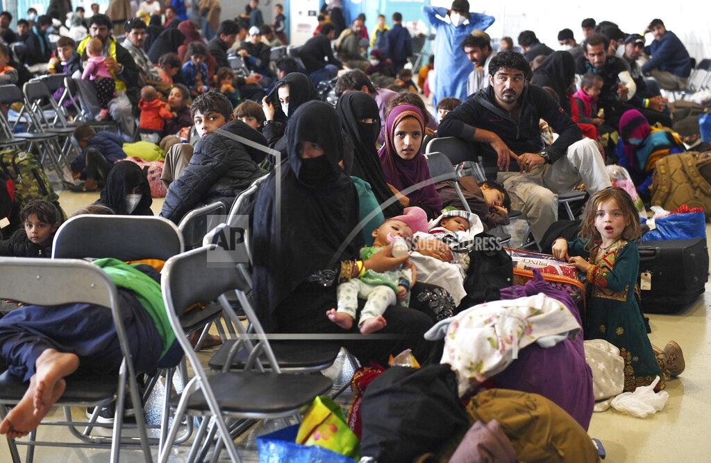 Olivier Douliery Afghan refugees are seated as they are being processed inside Hangar 5 at Ramstein Air Base in Germany, Wednesday, Sept. 8, 2021. (Olivier Douliery/Pool via AP)