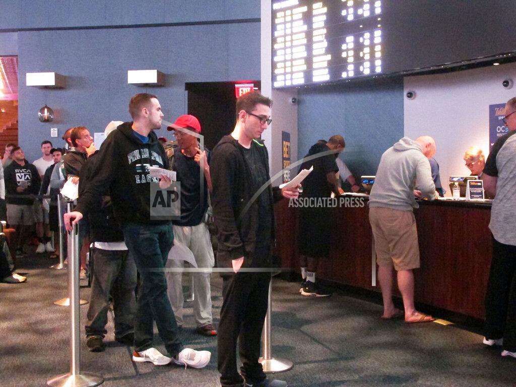 Customers line up to place wagers in the sports betting lounge at the Ocean Resort Casino in Atlantic City N.J. on Sept. 9, 2018. The coronavirus outbreak has added new wrinkles for bettors this year, but even so, the nation's sportsbooks expect a record year of bets on football in 2020 from an antsy public that has been cooped up for months amid the pandemic. (AP Photo/Wayne Parry)