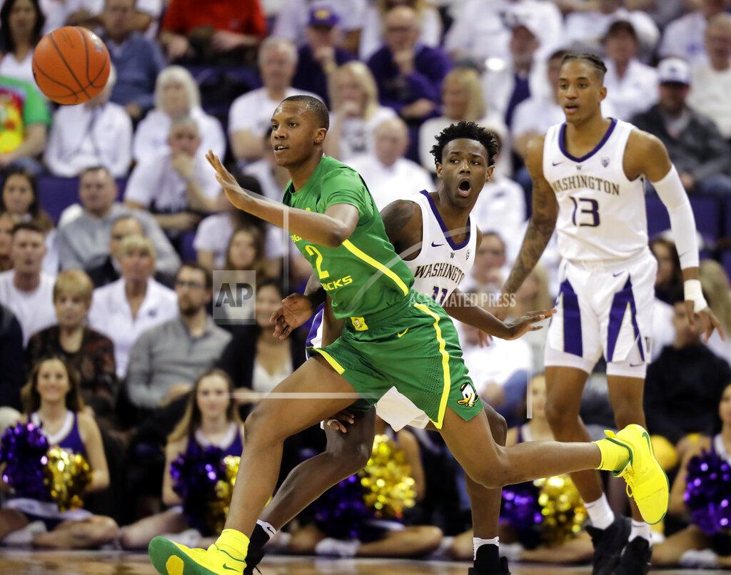 Ted S. Warren Oregon forward Louis King, left, passes around Washington forward Nahziah Carter, center, during the first half of an NCAA college basketball game, Saturday, March 9, 2019, in Seattle. (AP Photo/Ted S. Warren)