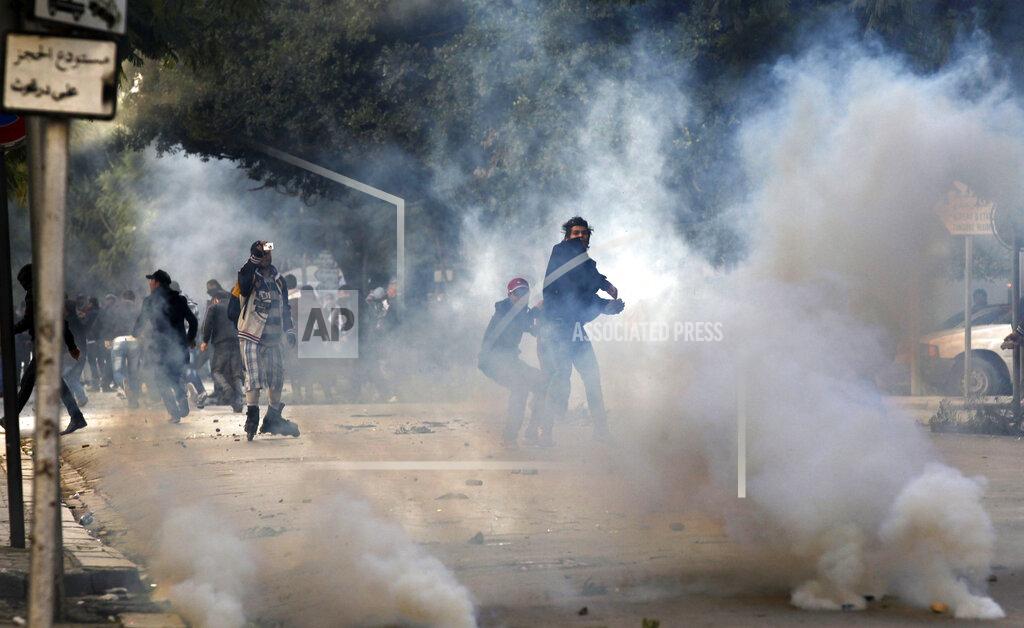 Christophe Ena FILE - In this file photo dated Friday, Jan. 14, 2011, a demonstrators throws a stone at police during clashes in Tunis. Tunisia's president declared a state of emergency and announced that he would fire his government as violent protests escalated Friday, with gunfire echoing in the North African country's usually calm capital and police lobbing tear gas at protesters. On Thursday Jan. 14, 2021, Tunisia commemorates 10 years since the flight into exile of its iron-fisted leader, Zine El Abidine Ben Ali, pushed from power in a popular revolt that foreshadowed the so-called Arab Spring.(AP Photo/Christophe Ena, FILE)