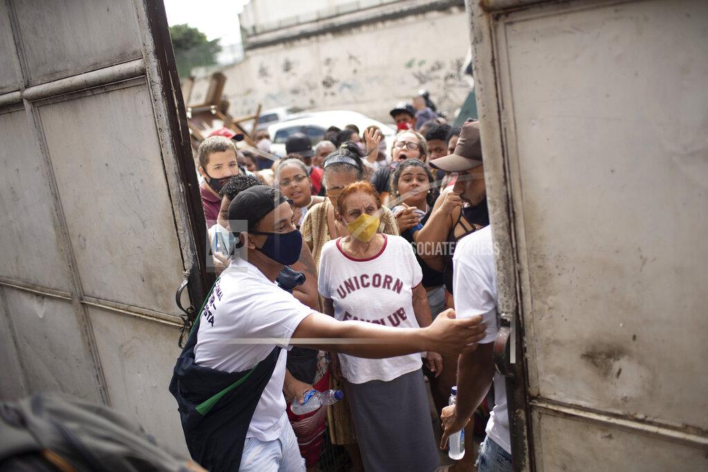 Silvia Izquierdo FILE - In this May 13, 2021 file photo, residents gather outside a gate for donated food from the Central Union of the Slums, known by its acronym CUFA, in the Jacarezinho favela of Rio de Janeiro, Brazil, amid the COVID-19 pandemic. As Brazil hurtles toward an official COVID-19 death toll of 500,000, President Jair Bolsonaro has waged a campaign to downplay the virus’s seriousness and keep the economy humming. (AP Photo/Silvia Izquierdo, File)