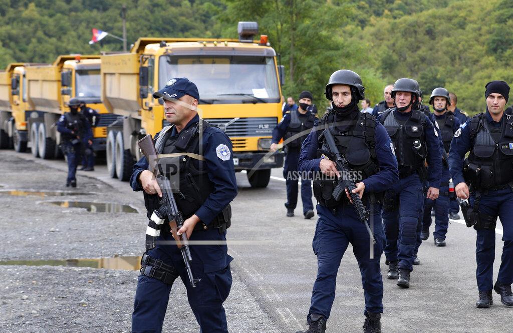 Bojan Slavkovic Kosovo police officers patrol by trucks where Kosovo Serbs block a road near the northern Kosovo border crossing of Jarinje, Monday, Sept. 20, 2021. Tensions soared Monday at the border between Kosovo and Serbia as Kosovo deployed additional police to implement a rule to remove Serbian license plates from cars entering Kosovo, while Serbs protested the move. (AP Photo/Bojan Slavkovic)