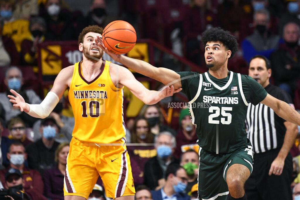 Craig Lassig Michigan State guard Malik Hall (25) reaches for a rebound before Minnesota forward Jamison Battle can get to it during the first half an NCAA college basketball game Wednesday, Dec. 8, 2021, in Minneapolis. (AP Photo/Craig Lassig)