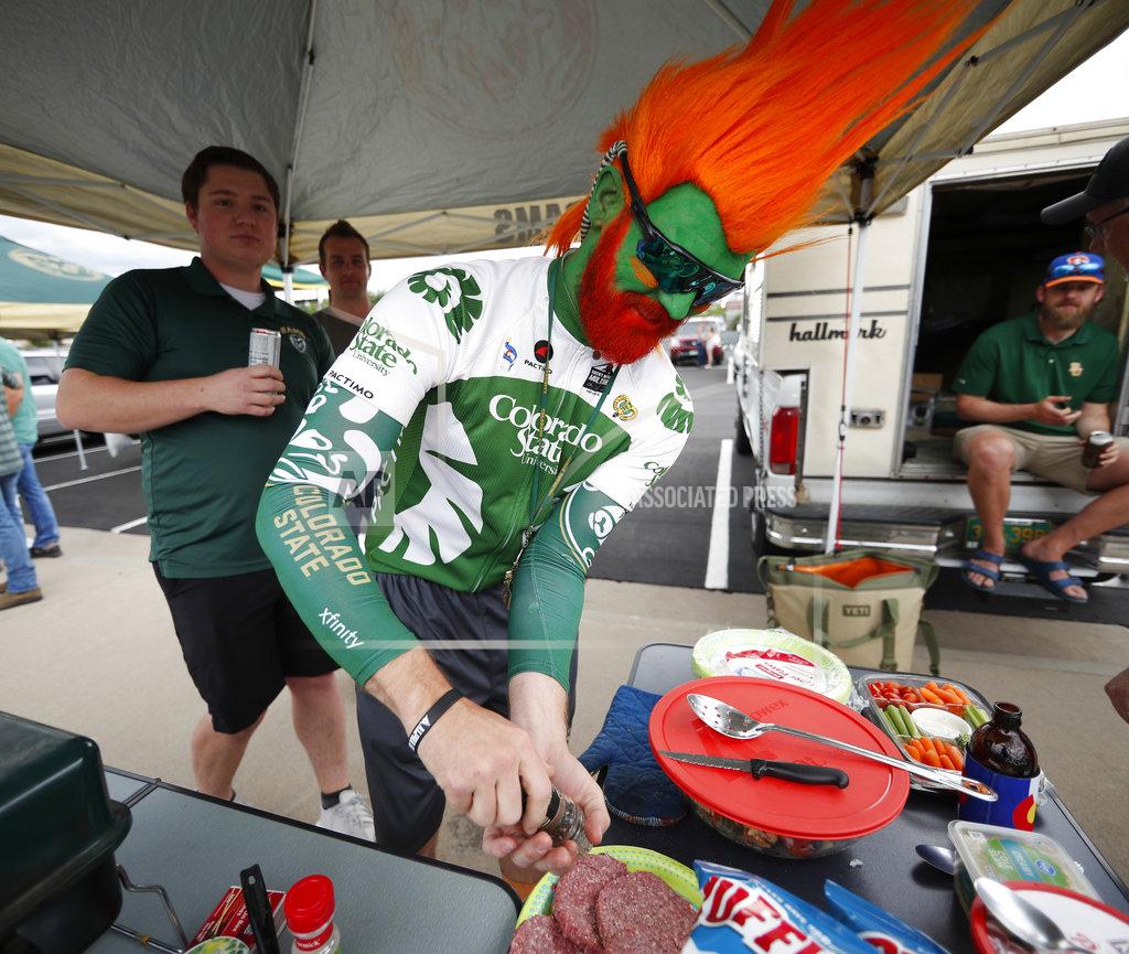 David Zalubowski Michael Lein-Weber, of Fort Collins, Colo., who attended Colorado State University, wears the school's colors as he prepares hamburgers while tailgating before Colorado State hosts Colorado in an NCAA college football game Friday, Aug. 31, 2018, in Denver. (AP Photo/David Zalubowski)