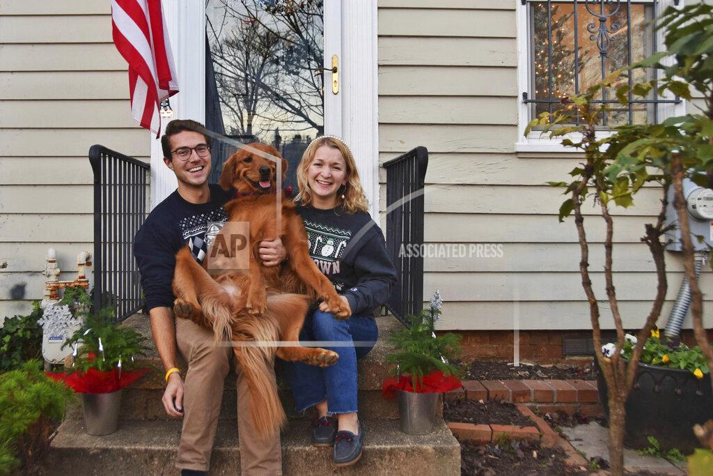 Olivia Hinerfeld In this photo provided by Olivia Hinerfeld, Olivia Hinerfeld poses with her boyfriend, Ryan Shymansky, and their golden retriever Lincoln on Dec. 6, 2020, in Washington. Jealous of the attention that Hinerfeld is paying to her video conference call, Lincoln,will fetch “the most disgusting” tennis ball he can find from his toy crate to drop into the lap of the Georgetown University Law School student. (Olivia Hinerfeld via AP)