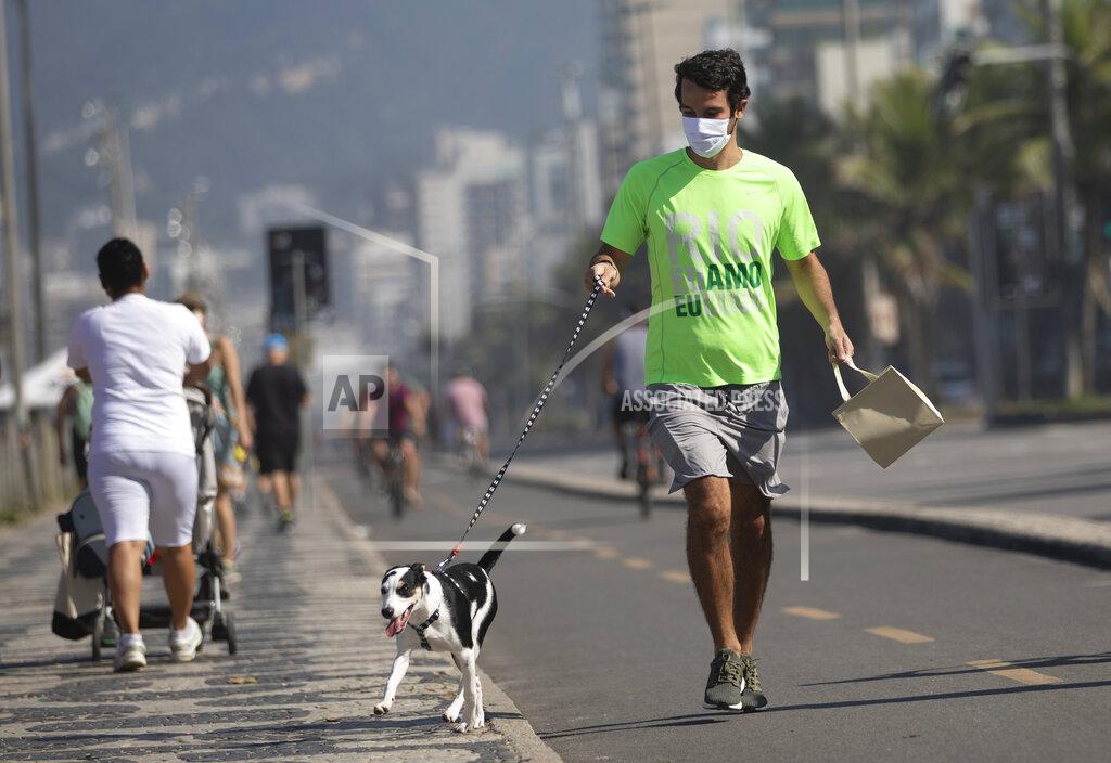 Silvia Izquierdo A man jogs with his dog in the bike lane that runs along the seashore at Ipanema beach in Rio de Janeiro, Brazil, Tuesday, June 2, 2020, amid the new coronavirus pandemic. Rio, the city with the second-most cases after Sao Paulo, is beginning to gradually relax restrictions on Tuesday, allowing people to exercise on the beachfront sidewalk and practice individual activities in the sea. (AP Photo/Silvia Izquierdo)