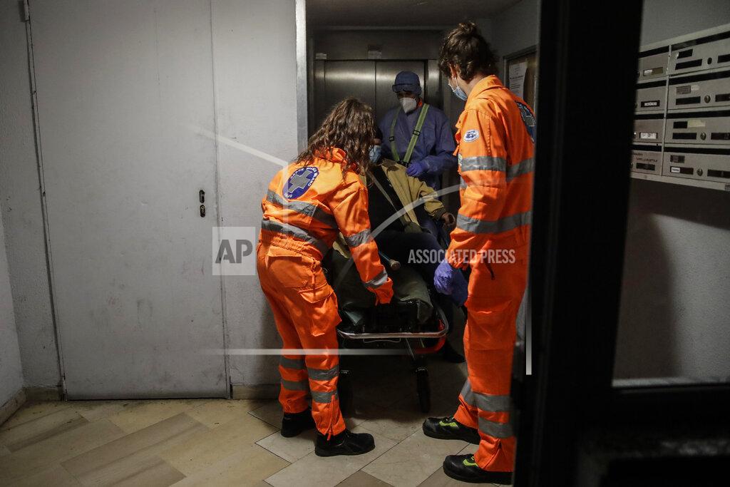 Luca Bruno From left, medical volunteer Beatrice Ammattatiello, medical staffers Paolo Pozzoli and Andrea Arosio, right, carry a suspected Covid patient in the hall of an apartment building during their shift with the emergency White Cross ambulance, in Cinisello Balsamo, near Monza, Italy, Thursday, Nov. 19, 2020. The city of Monza north of Milan is best known for its Formula 1 racetrack. In 2020, it has been the ambulance service that has been doing most of the racing. Over three days that an Associated Press photographer traveled on night calls with an ambulance service, the Monza-Brianza province of some 875,000 bordering Milan added 2,500 new cases, part of Italy’s new epicenter in the Lombardy region. (AP Photo/Luca Bruno)