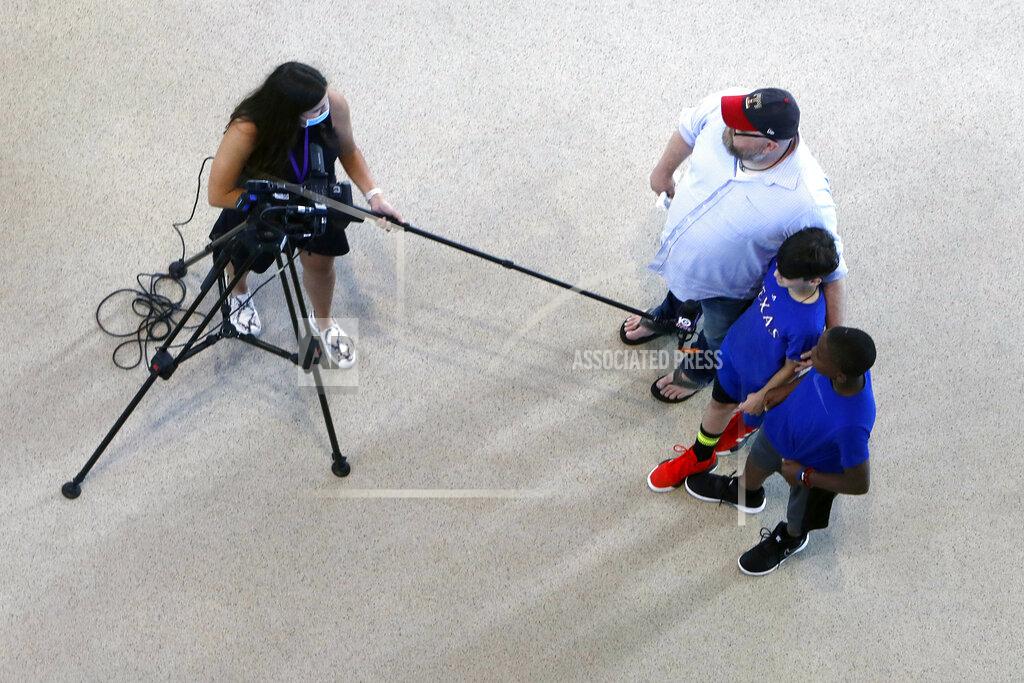 A member of the media uses a long microphone boom to interview Texas Rangers baseball fans during the first day of public tours at Globe Life Field, home of the Texas Rangers baseball team, in Arlington, Texas, Monday, June 1, 2020. The coronavirus pandemic has forced sports teams and their leagues to evaluate how they will welcome back fans. (AP Photo/LM Otero)