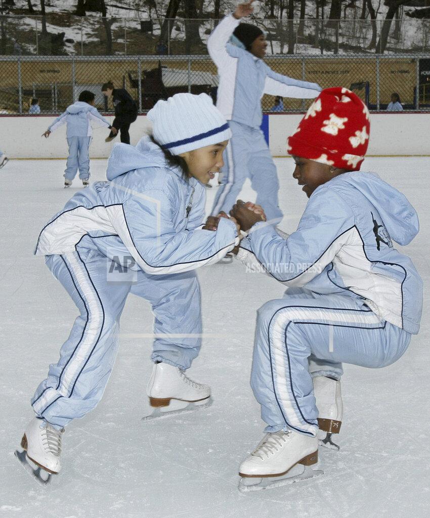 FILE - Eight-year-olds Tatiyana Jenkins, left, and Florence Ngala, members of Figure Skating in Harlem, warm up in a donut spin at Lasker Ice Rink in New York's Central Park in this Saturday, Feb. 7, 2004, file photo. Due to the COVID-19 pandemic, the members of the 24-year-old organization that serves young women of color in New York City didn't see the ice from late winter until fall. The program's objective for nearly a quarter-century has been helping girls of color transform their lives by growing in confidence, leadership and academic achievement. (AP Photo/Ed Bailey, File)