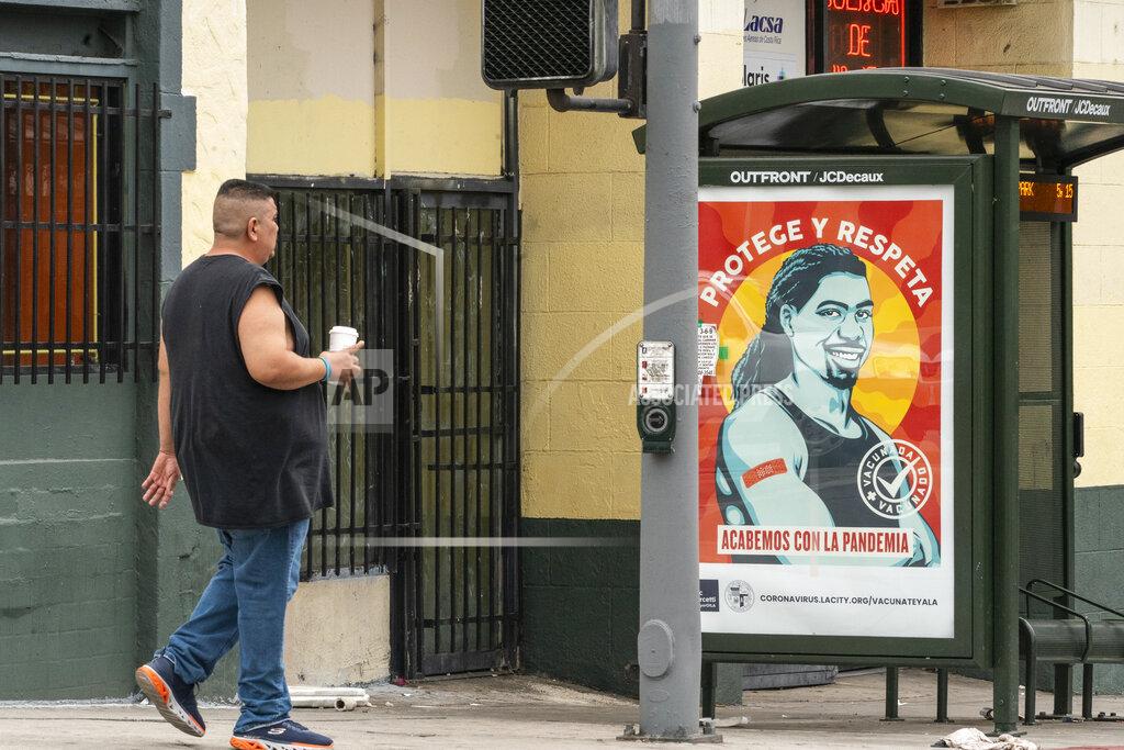 Damian Dovarganes A pedestrian walks past a banner promoting vaccinations at the Pico-Union district in Los Angeles, Monday, July 26, 2021. The City of Los Angeles advertisement reads in Spanish: "Protect and Respect, Let's End the Pandemic." Pico-Union is the fourth most dense neighborhood in Los Angeles, home to a large immigrant community. The state of California said it would require proof of vaccination or weekly testing for all state workers and millions of public- and private-sector health care employees starting in August. (AP Photo/Damian Dovarganes)