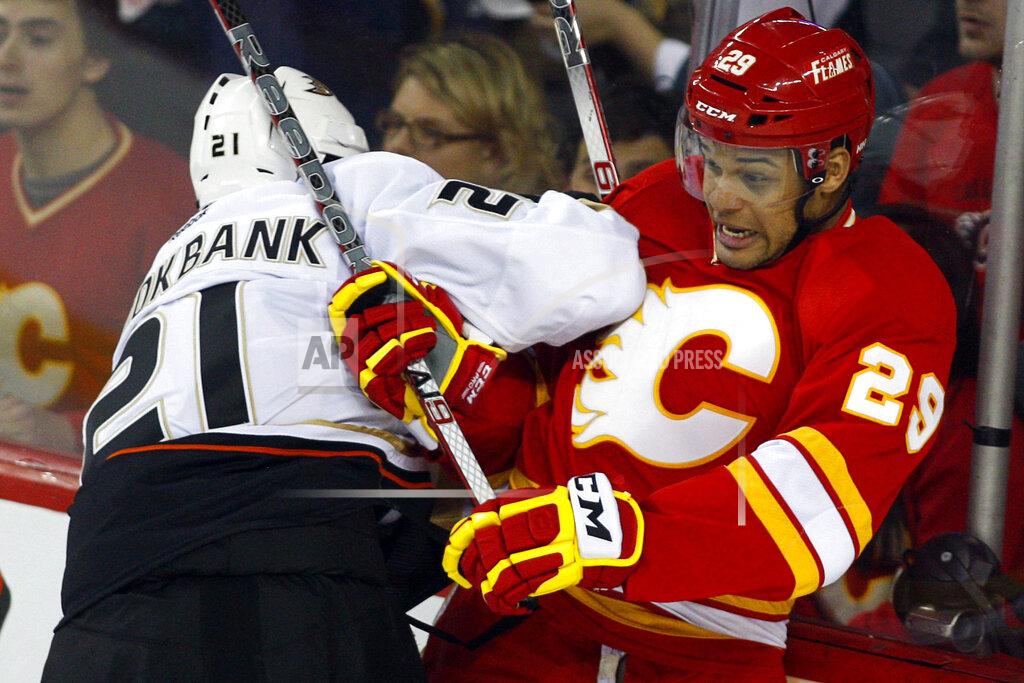 Jeff Mcintosh FILE - In this April 7, 2012, file photo, Anaheim Ducks' Sheldon Brookbank, left, checks Calgary Flames' Akim Aliu, a Nigerian-born Canadian, during third period NHL hockey action in Calgary, Alberta. Calgary Flames general manager Brad Treliving said the team is looking into an accusation that head coach Bill Peters directed racial slurs toward a Nigerian-born hockey player a decade ago in the minor leagues, then arranged for the player’s demotion when he complained. Akim Aliu tweeted Monday, Nov. 25, 2019, that Peters “dropped the N bomb several times towards me in the dressing room in my rookie year because he didn’t like my choice of music.” (AP Photo/The Canadian Press, Jeff McIntosh, File)