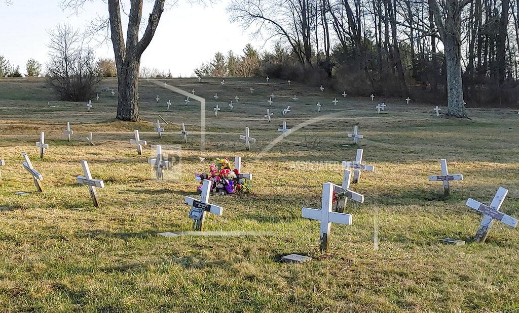 Kelly Monitz Phil Jeffries, retired funeral director and deputy coroner for Carbon County, Pa., placed a marker behind the flowers on the right, on Beth Doe and her baby’s grave with their true identities, Evelyn and Emily Grace Colon, after more than four decades, in Laurytown Road Cemetery in Lehigh Township, Pa., Sunday, April 4, 2021. Flowers and a child's toy also adorn the grave. Colon, who was known for decades here in Northeast Pennsylvania as Beth Doe, was brutally murdered and dumped off an Interstate 80 bridge in East Side borough in December 1976. (Kelly Monitz/Standard-Speaker via AP)