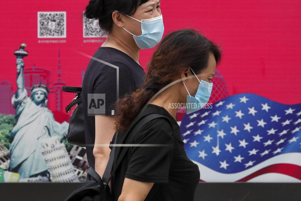 Andy Wong Women wearing face masks to help protect against the coronavirus walks by an advertising board displaying an American flag and Statue of Liberty on a street in Beijing, Thursday, Aug. 6, 2020. China's biggest recent outbreak of coronavirus has grown slightly. Hundreds people have developed COVID-19 in the far northwestern region of Xinjiang, with more than dozens of new cases reported Thursday in its capital and largest city, Urumqi. (AP Photo/Andy Wong)