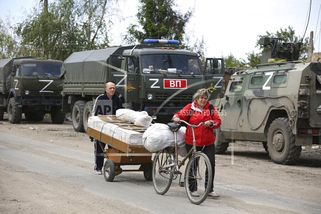 Alexei Alexandrov Local residents walk past Russian military vehicles in Mariupol, in territory under the government of the Donetsk People's Republic, eastern Ukraine, Tuesday, May 17, 2022. (AP Photo/Alexei Alexandrov)