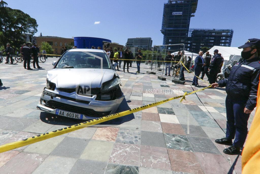 Hektor Pustina A police officer stands near to a damaged car on central Skanderbeg square, after an incident, in Tirana, Sunday, April 25, 2021. A man drove his car into the Albanian capital Tirana’s main square where vehicles are not allowed, the local media and police reported on Sunday. The driver broke the barriers to enter the Skanderbeg Square. A young man managed to stop the driver entering from the window. Then people dragged him out of the car. No one was injured. The car stopped near two big tents where people get vaccines and a smaller tent raised from the Syri Televizion private channel to cover the voting. (AP Photo/Hektor Pustina)