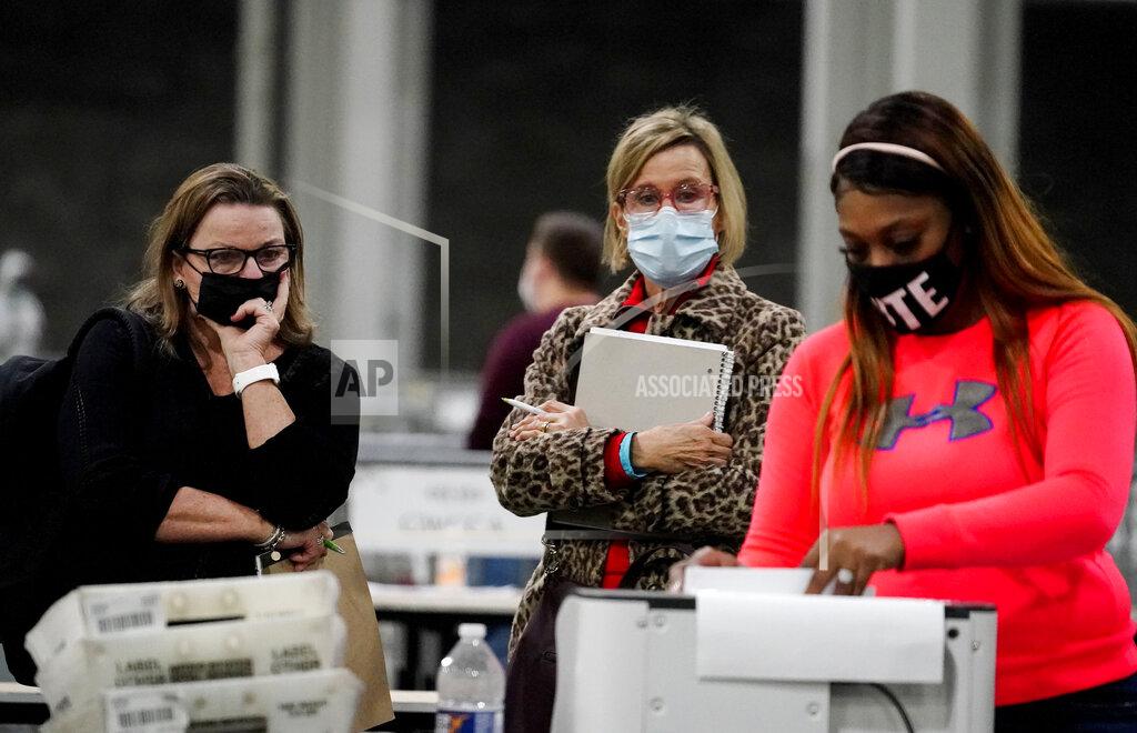 Brynn Anderson Observers watch an official work as ballots are counted for Georgia's Senate runoff election at the Georgia World Congress Center on Wednesday, Jan. 6, 2021, in Atlanta. (AP Photo/Brynn Anderson)
