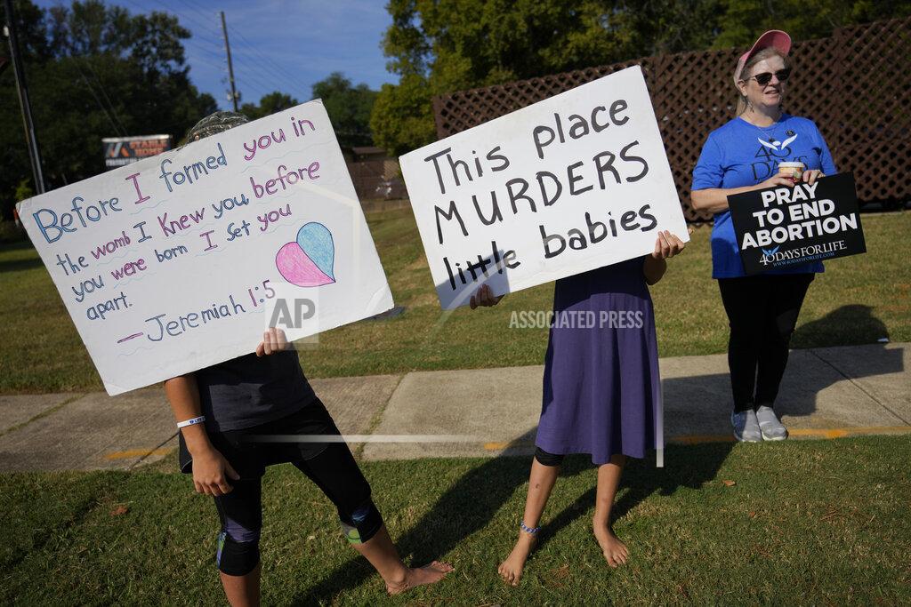 Rebecca Blackwell Anti-abortion protesters, including two adolescent girls, hold signs as they stand outside Hope Medical Group for Women, Saturday, Oct. 9, 2021, in Shreveport, La. As most of the women entered the clinic's parking lot, they were met by two groups of anti-abortion protesters, mostly men from East Texas who regularly make the trip to Shreveport. (AP Photo/Rebecca Blackwell)