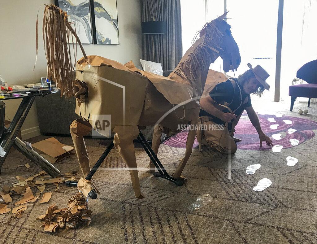 David Marriott poses with his paper horse in his hotel room in Brisbane, Australia, April 3, 2021. While in quarantine inside his Brisbane hotel room, art director Russell Brown was bored and started making a cowboy outfit from the paper bags his meals were being delivered in. His project expanded to include a horse and a clingfilm villain that he has daily adventures with, in images that have gained a huge online following. (David Marriott via AP)