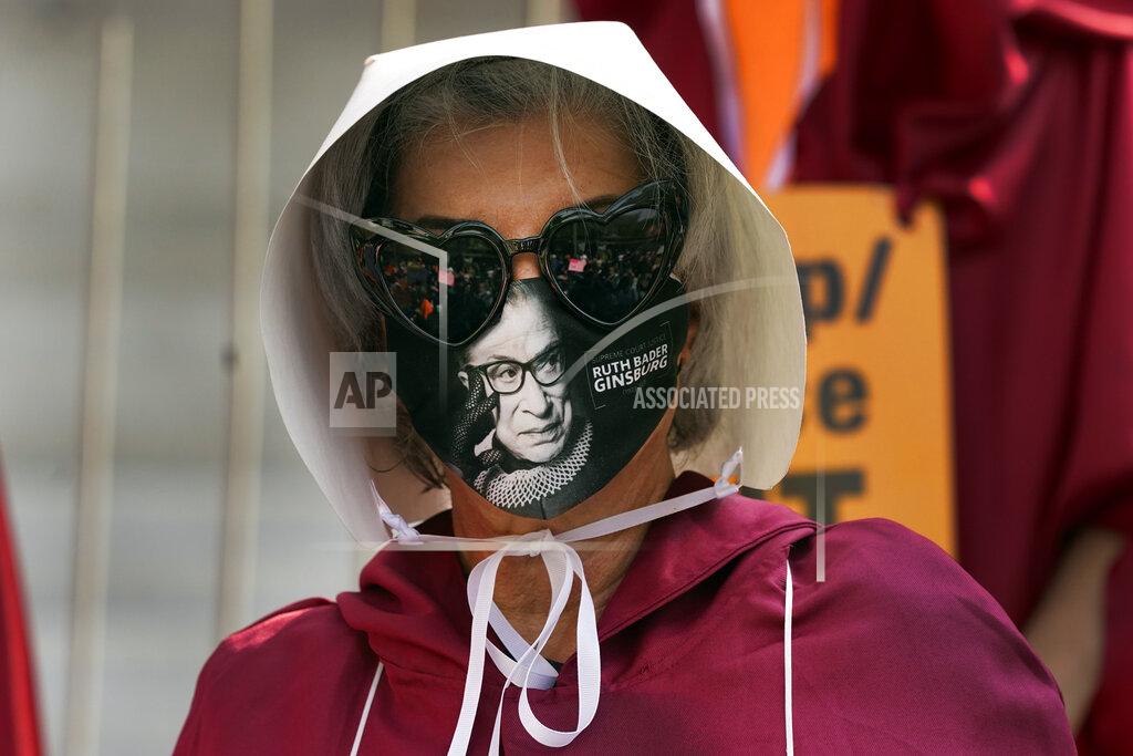 Marcio Jose Sanchez A demonstrator wears a mask with an image of Supreme Court judge Ruth Bader Ginsburg on it during a Women's March Saturday, Oct. 17, 2020, in Los Angeles. Thousands of women rallied in U.S. cities, to oppose President Donald Trump and his fellow Republican candidates in the Nov. 3 elections. (AP Photo/Marcio Jose Sanchez)
