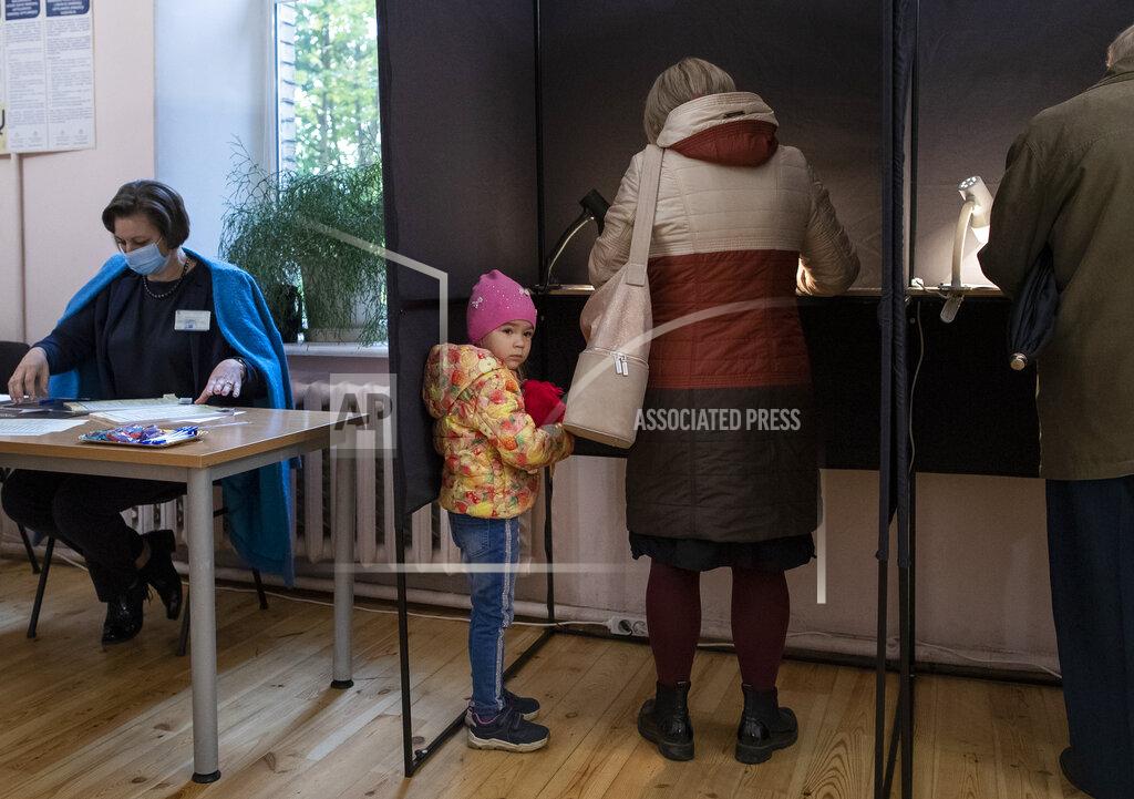 Mindaugas Kulbis A child looks out of booth at a polling station during parliamentary elections in Vilnius, Lithuania, Sunday, Oct. 11, 2020. Polls opened Sunday for the first round of national election in Lithuania, where voters will renew the 141-seat parliament and the ruling four-party coalition is widely expected to face a stiff challenge from the opposition to remain in office. (AP Photo/Mindaugas Kulbis)