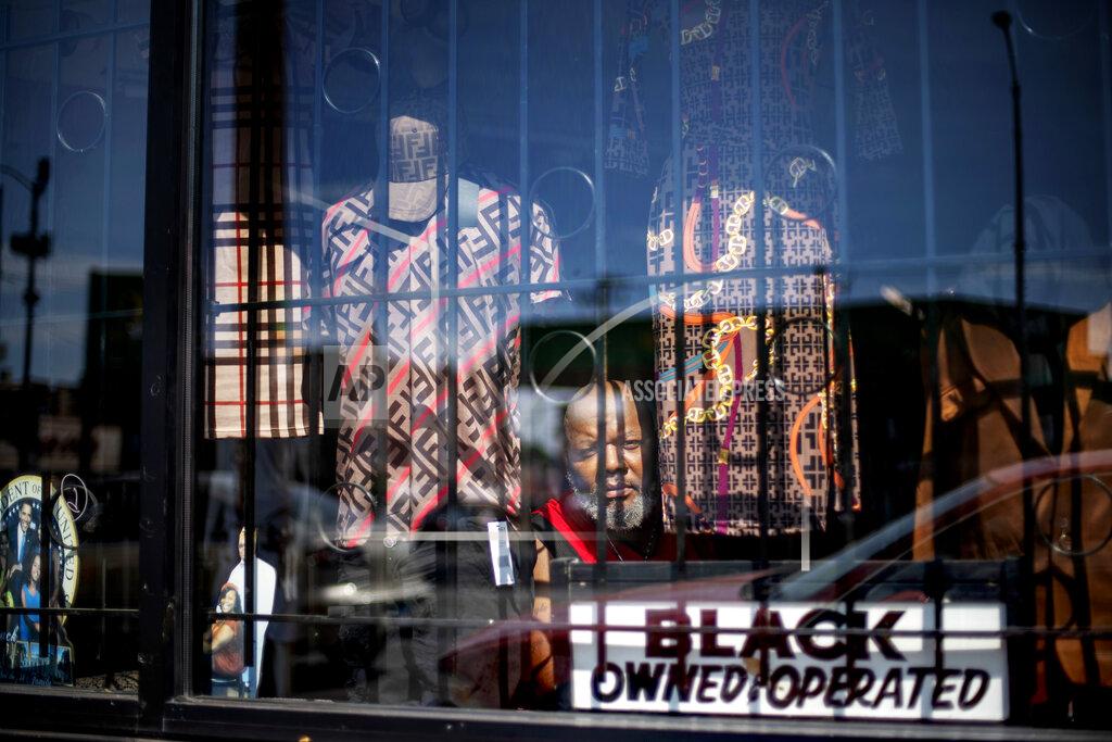 David Goldman Ronald Cashaw looks out from the window of his clothing store, Just Kicking, in the Auburn Gresham neighborhood of Chicago, Saturday, Aug. 22, 2020. Blocked by security bars, looters smashed the front window of his store grabbed some clothing and ran away before Cashaw arrived. "I had tears in my eyes," says Cashaw. The looting was something new, and horrible. But in the nearly two decades Cashaw has served this community, financial problems have grown more devastating. (AP Photo/David Goldman)