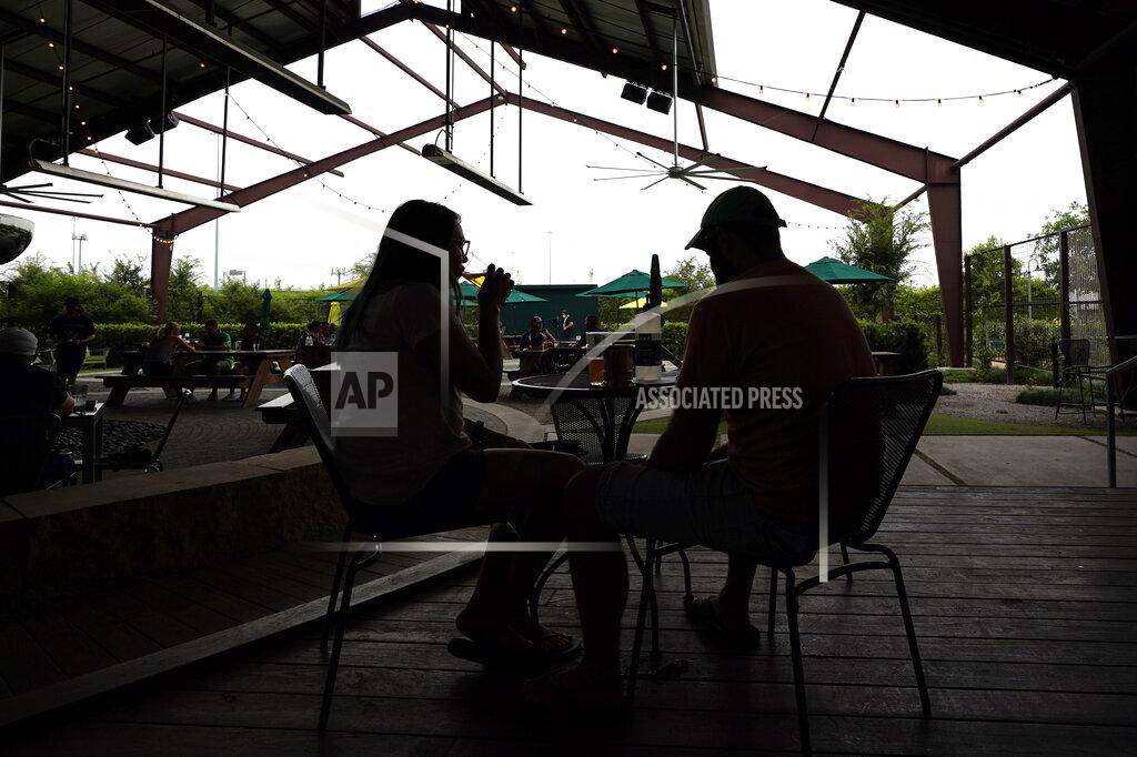 David J. Phillip Leslie Roades, left, and David Schmitz drink beer at the Saint Arnold Brewing Company, Friday, June 26, 2020, in Houston. Texas Gov. Greg Abbott announced Friday that he is shutting bars back down and scaling back restaurant capacity to 50%, in response to the increasing number of COVID-19 cases in Texas. (AP Photo/David J. Phillip)