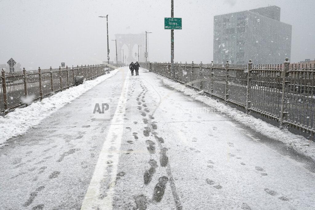 Kathy Willens Pedestrian footsteps are visible on the path leading to the Brooklyn Bridge as another winter snowstorm, the second in less than a week, buffeted the Northeast, Sunday, Feb. 7, 2021, in New York. (AP Photo/Kathy Willens)